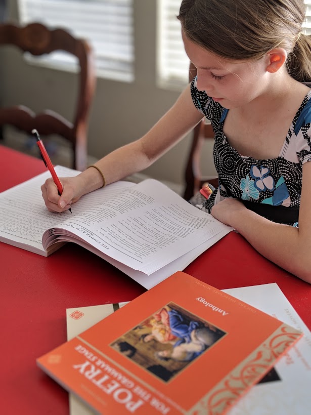 girl sitting at table doing work in poetry homeschool curriculum