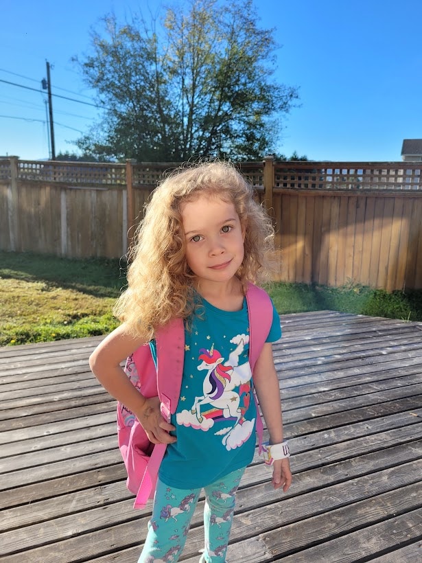 lenora in teal unicorn outfit with pink backpack on first day of homeschool kindergarten
