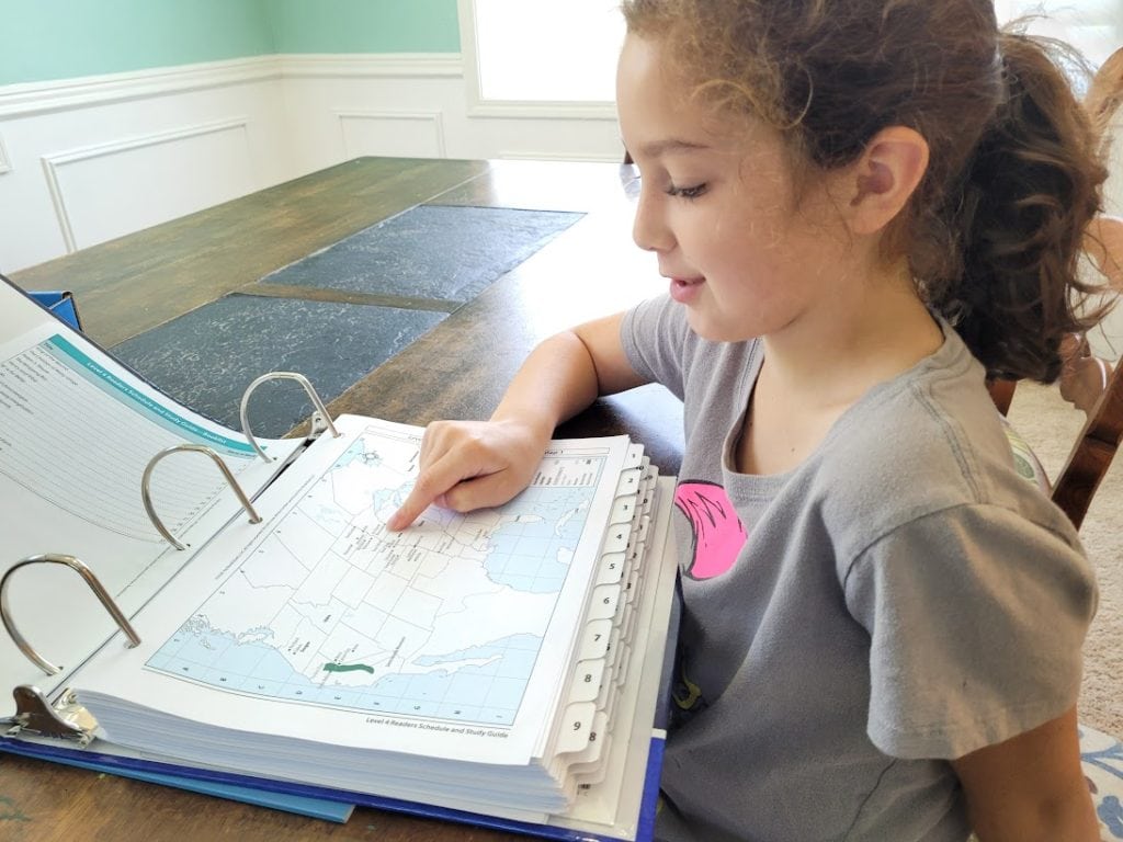 little girl at table pointing to a map of the United States 