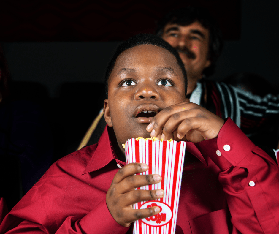 boy eating popcorn in movie theater